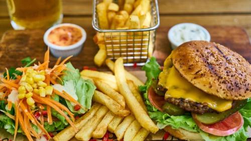 a plate with a hamburger and french fries and a basket of french fries at Jebel Hotel & Lounge Buloba in Kampala