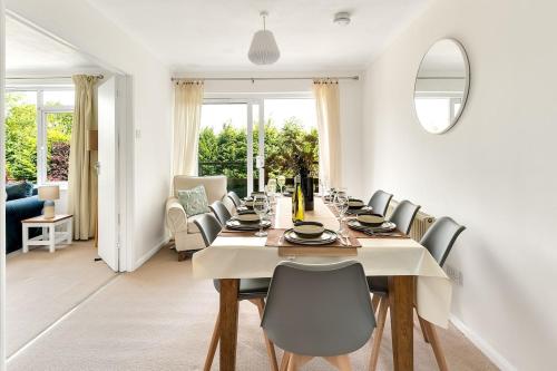 a white dining room with a long table and chairs at Cornish house 5 min drive to beach in Falmouth