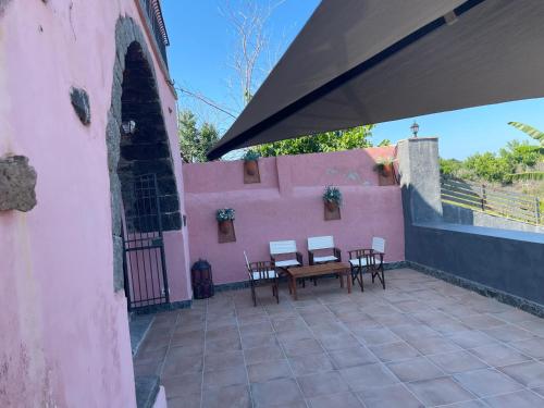 a patio with a table and chairs on a pink wall at Le Decime in Mascali