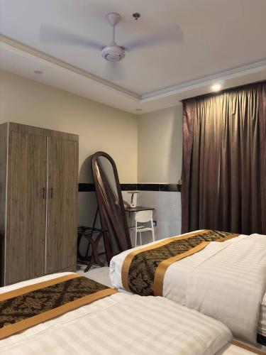 a hotel room with two beds and a table at سحاب الأندلس للشقق المخدومة 2 أملج Sahab Al Andalus for Served Apartments in Umm Lujj