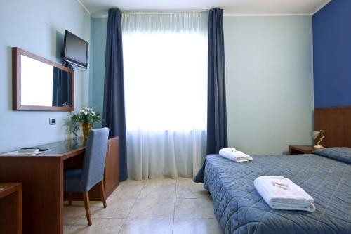 a bedroom with a bed and a desk and a window at Hotel San Martino in Cassibile
