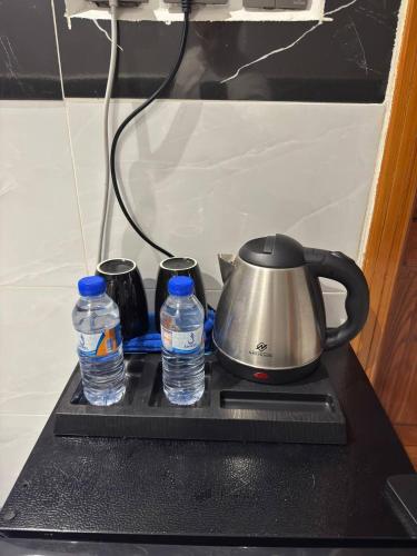 a tea kettle and two bottles of water on a stove at سحاب الأندلس للشقق المخدومة 2 أملج Sahab Al Andalus for Served Apartments in Umm Lujj