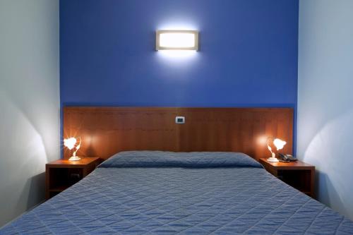 a bedroom with a blue wall and a bed with two lights at Hotel San Martino in Cassibile
