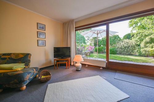 un soggiorno con divano, TV e ampia finestra di Bungalow Mumm a Dahme