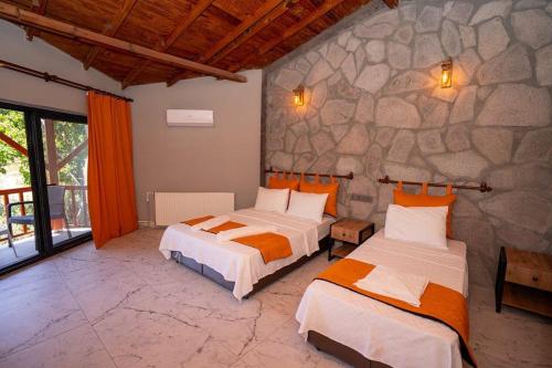 a bedroom with two beds and a stone wall at Sokakağzı Otel & Beach in Ayvacık