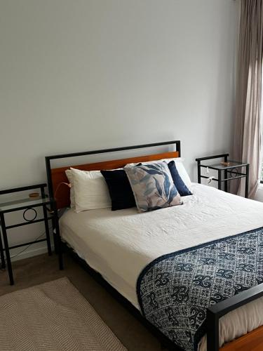 a bedroom with a bed with white sheets and pillows at Casual comfort in Byron Shire in Mullumbimby