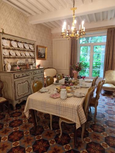 une salle à manger avec une table et un lustre dans l'établissement La Villa Romaine, à Montmirey-la-Ville