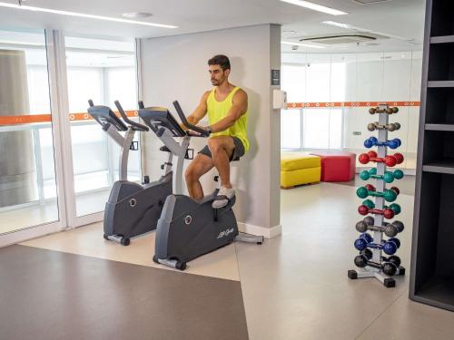 a man sitting on a treadmill in a gym at Mercure Jundiai Shopping in Jundiaí