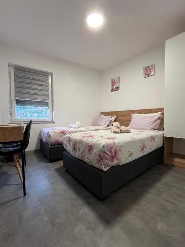 a bedroom with two beds and a desk and a table at Apartmani Venecia in Prozor