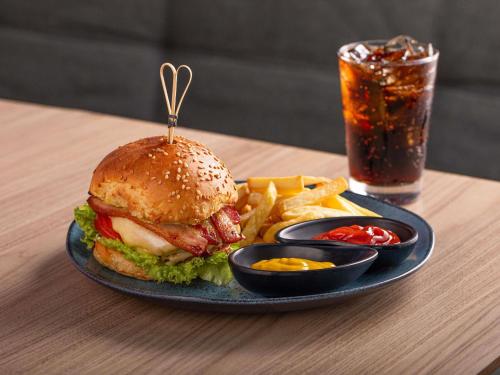 a sandwich and french fries on a plate with a drink at Mercure Jundiai Shopping in Jundiaí