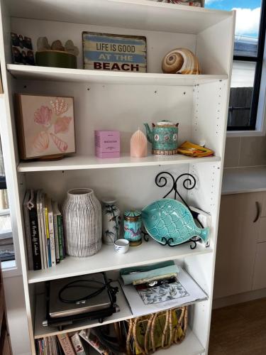a white book shelf filled with lots of items at Casual comfort in Byron Shire in Mullumbimby