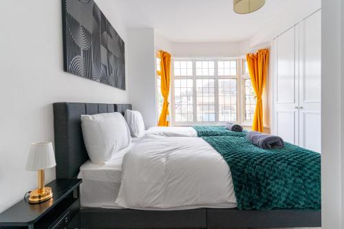 ein Schlafzimmer mit einem Bett mit einer grünen Decke darauf in der Unterkunft NEW Spacious House 6 Bedrooms 4Bathrooms 10 Guests in Romford