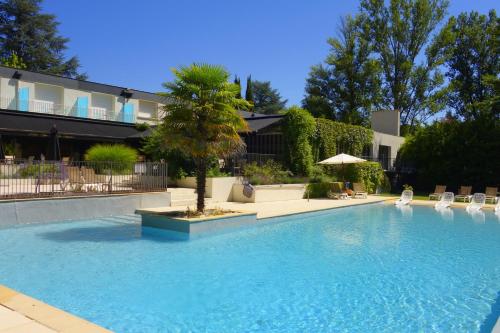 une grande piscine avec un arbre en face d'un bâtiment dans l'établissement Hôtel La Ségalière Spa Bar, à Cajarc