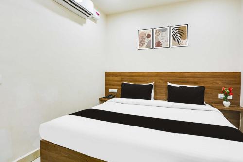 a bedroom with a white bed with a wooden headboard at Hotel O Clock Tower Ludhiana in Ludhiana