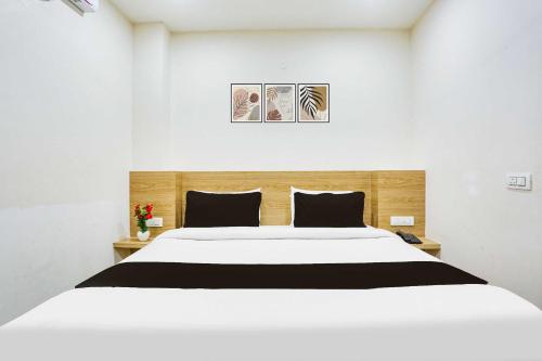 a white bedroom with a large white bed with black pillows at Hotel O Clock Tower Ludhiana in Ludhiana