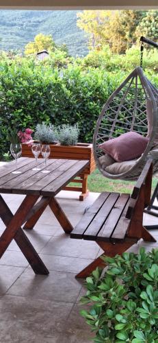 a wooden picnic table with a swing and two wine glasses at Villa Oaza Verde in Herceg-Novi