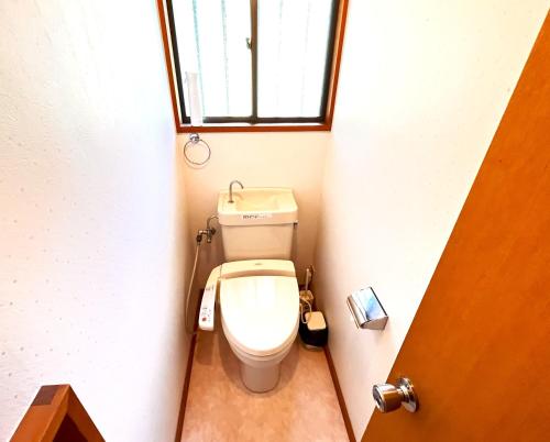 a toilet in a small bathroom with a window at りす村別荘 in Yamanakako