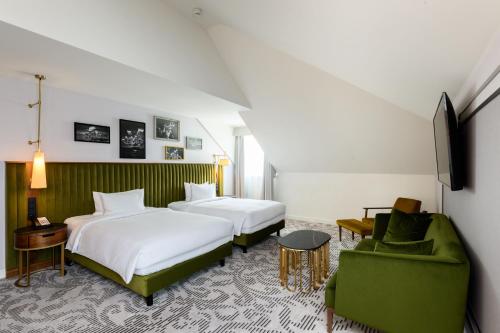 a hotel room with two beds and a green chair at Hotel Saski Krakow Curio Collection by Hilton in Kraków