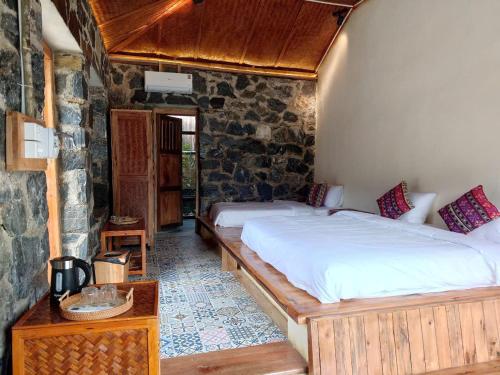 a bedroom with a large bed in a stone wall at Ha Giang Ecolodge in Ha Giang