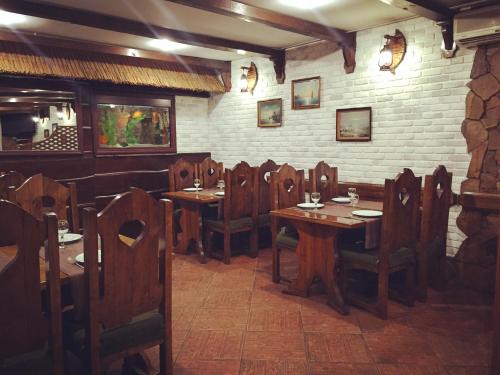 a restaurant with wooden tables and chairs and a brick wall at Nakhodka Inn in Mykolaiv