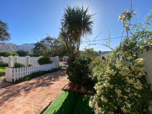 a white fence with a palm tree in a garden at Fig Tree in Montagu