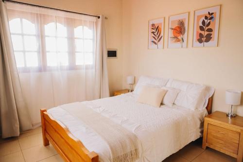 a bedroom with a white bed with a window at Casita Catiri - Cozy Guesthouse with a Pool in Noord