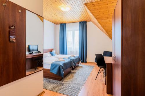 a bedroom with a bed and a desk and a television at Hotel Rozálka in Pezinok