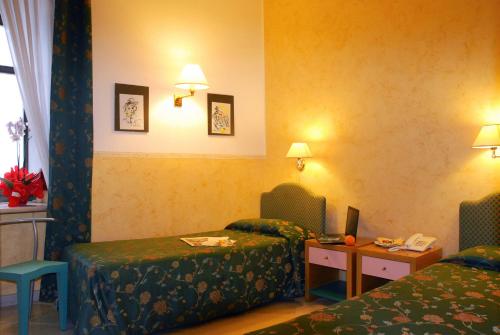 a hotel room with two beds and a table with a desk at Park Hotel Villa Americana in Rodi Garganico