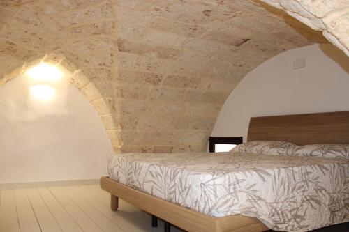 a bedroom with a bed with a stone wall at CRISTALLI Home in Galatina