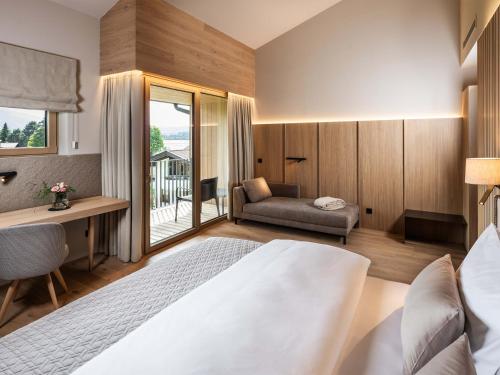 a bedroom with a bed and a desk and a chair at Schlosshotel Mitterhart in Schwaz