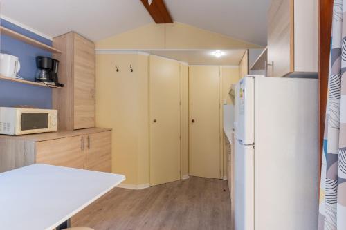 a kitchen with a white refrigerator and wooden cabinets at Les Rives d’Auzon Mobil-home 6 pers in Lavilledieu