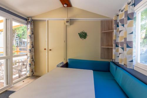 a room with a blue couch and a window at Les Rives d’Auzon Mobil-home 6 pers in Lavilledieu