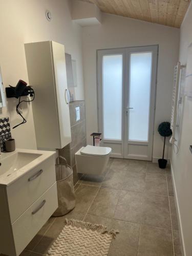 a white bathroom with a toilet and a sink at Maison cosy in Ambarès-et-Lagrave
