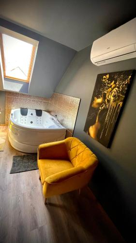 a bathroom with a bath tub and a yellow chair and a tub at Greyhouse Apartments in Harkány