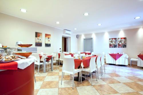 a dining room with tables and white chairs at Hotel San Martino in Cassibile