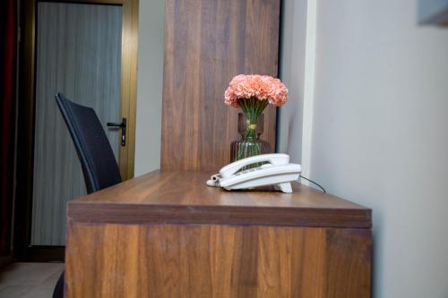 a desk with a phone and a vase of flowers at Mémorial Hôtel in Ouagadougou