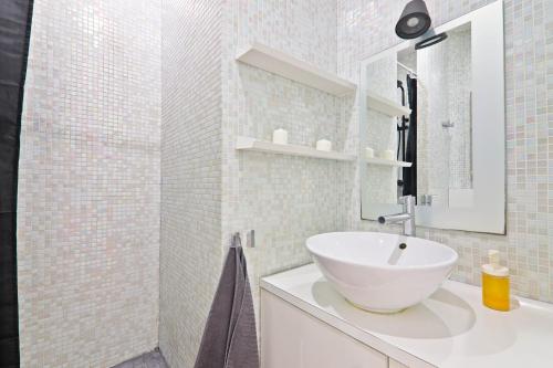 une salle de bain blanche avec un lavabo et un miroir dans l'établissement 1 Bedroom Apartment - 6P - Republique, Paris, à Paris
