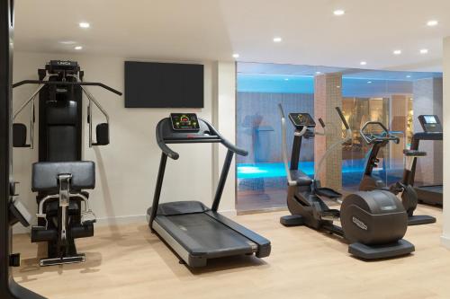 a gym with three tread machines and a tv at H10 Casa del Mar in Santa Ponsa