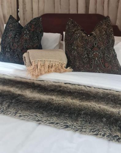 un letto con coperte grigie e cuscini sopra di Lala Panzi a Ghanzi