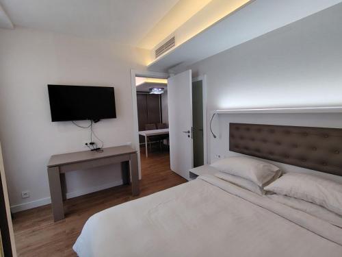 a bedroom with a white bed and a television at PANORAMA Apartments BATUMI in Batumi