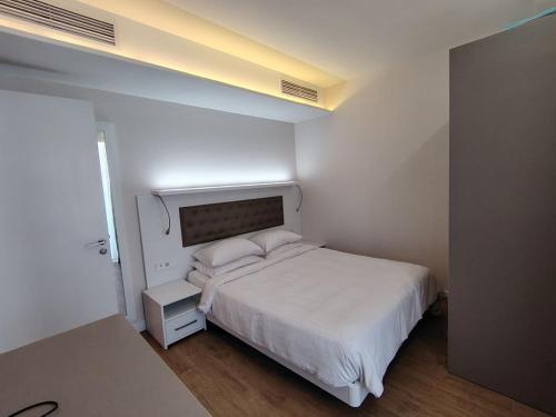 a small bedroom with a white bed and a table at PANORAMA Apartments BATUMI in Batumi