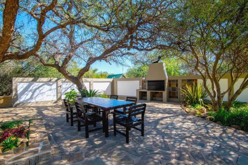 a patio with a table and chairs under a tree at Arebbusch Travel Lodge in Windhoek