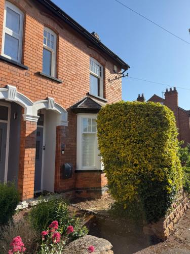 ein Backsteinhaus mit einem Busch davor in der Unterkunft West Bridgford 2 Bed 2 Bathroom Apartment with parking in Nottingham