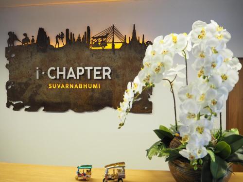 a table with a vase of flowers and a painting at iChapter Hotel Suvarnabhumi in Samutprakarn