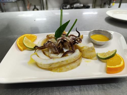 a plate with a seafood dish with oranges and dipping sauce at Telvina Beach Lodge in Vilanculos