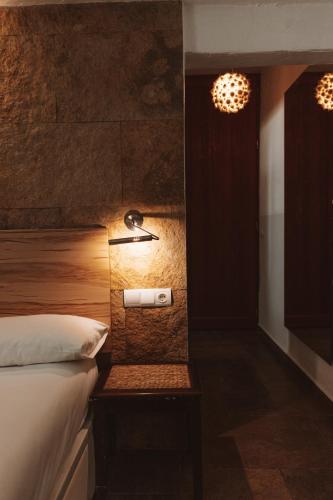 a bedroom with a bed and a nightstand with a lamp at Los Pilares de Ronda Boutique & Hotel in Ronda
