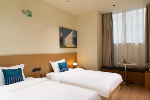 a hotel room with two beds and a window at Xiamen Evening Breeze Hotel in Xiamen