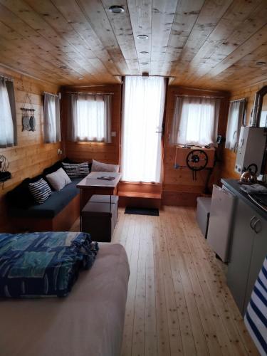 a room with a bed and a couch in a cabin at 2-person gîte on Laïta boat in Cheffes-sur-Sarthe