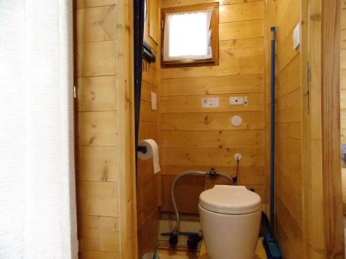 a bathroom with a toilet in a wooden wall at 2-person gîte on Laïta boat in Cheffes-sur-Sarthe