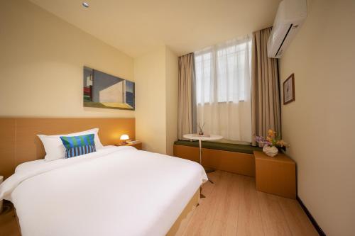 a bedroom with a large white bed and a window at Xiamen Evening Breeze Hotel in Xiamen